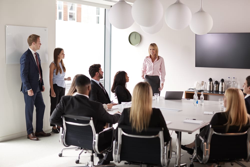Mature Businesswoman Addressing Group Meeting Around Table At Graduate Recruitment Assessment Day